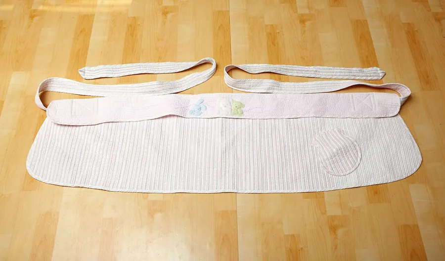 Fabric baby carrier laid flat on a wooden floor