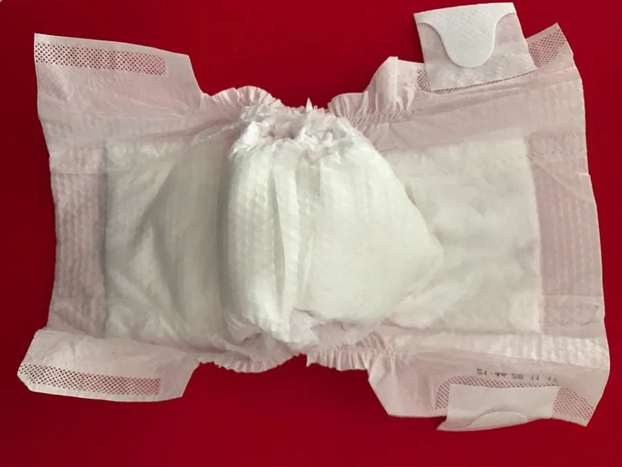 Unfolded disposable diaper on a red background