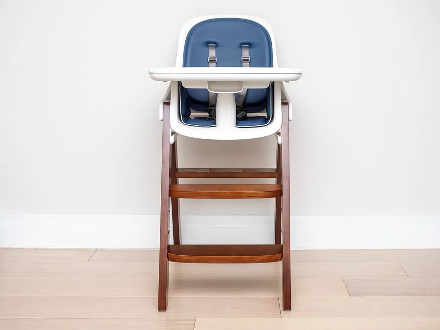 Wooden high chair with a white tray and blue seat pad