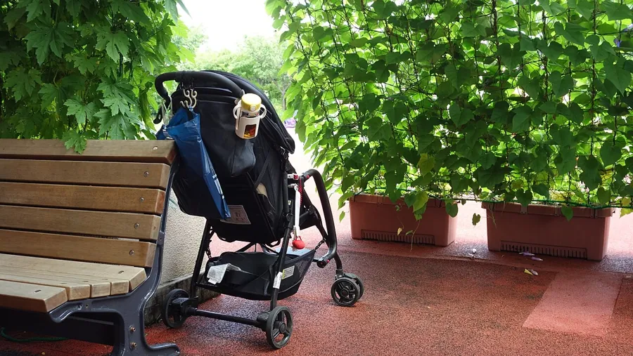 Folded city stroller parked beside a bench